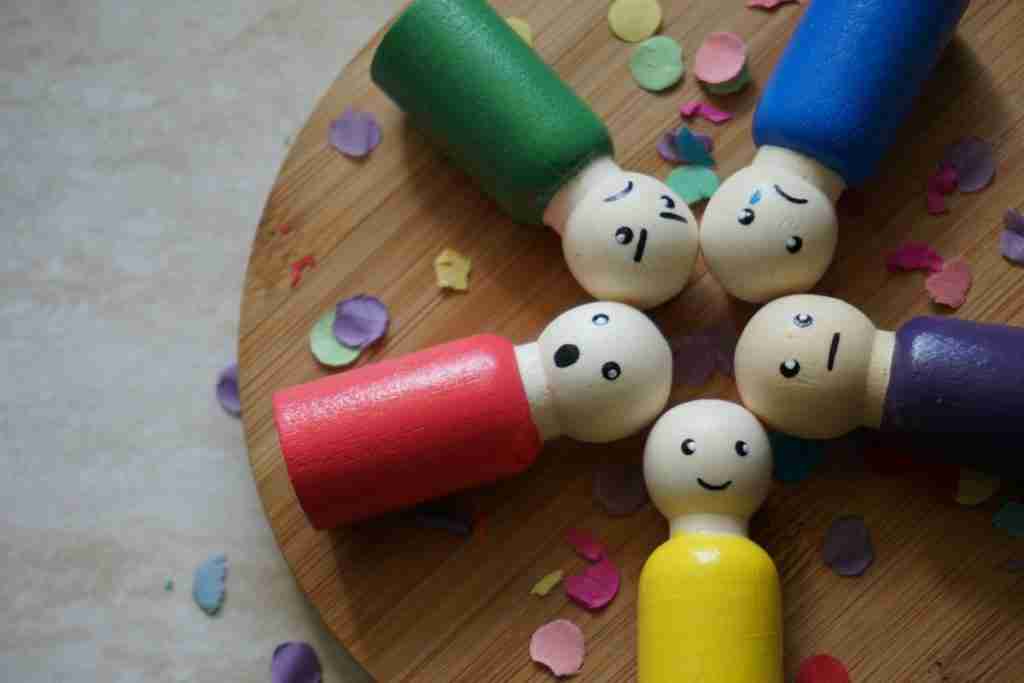 Regolare le emozioni rappresentato da birilli di legno con faccine emotive di diverse emozioni